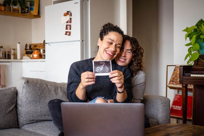 Happy expecting couple smiling with sonogram picture on video chat