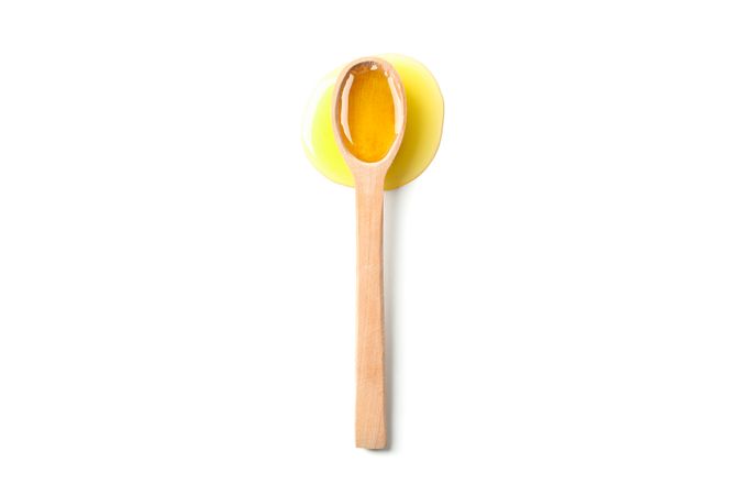 Wooden spoon with honey isolated on plain background, top view