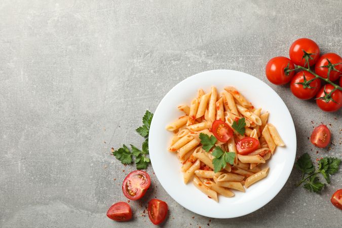 Composition with plate of tasty pasta on gray background, top view
