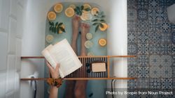 Top view of woman holding a book laying a bathtub 56EPj0