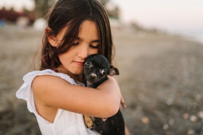 Girl with little dog on sandy beach