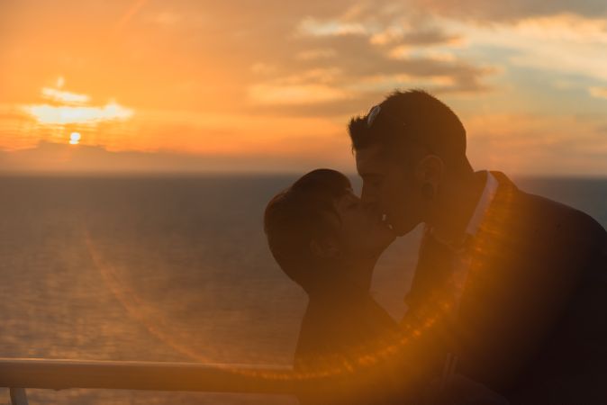 Young people kissing in sunset light on ship