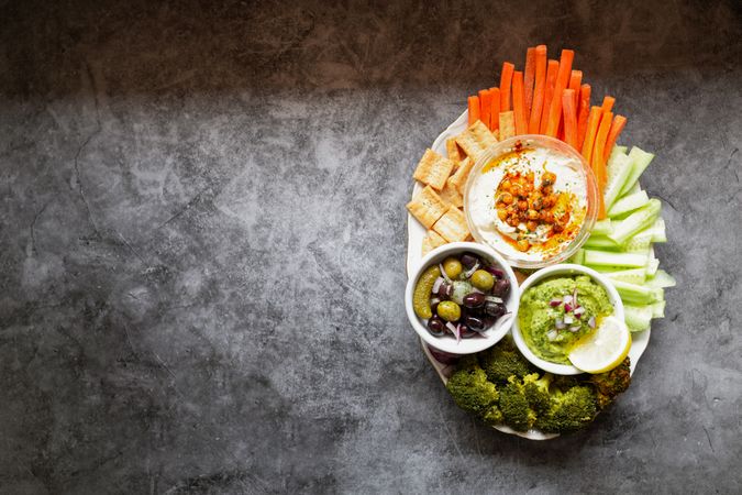 Tasty hummus and sauces decorated with bright cut vegetables on table