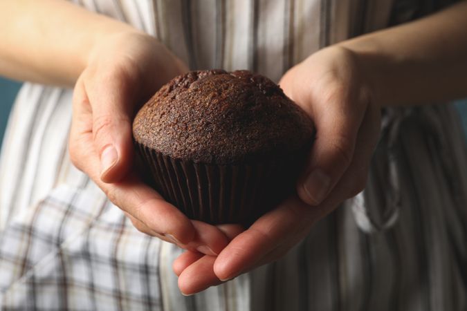 Woman holds tasty chocolate muffin, close up