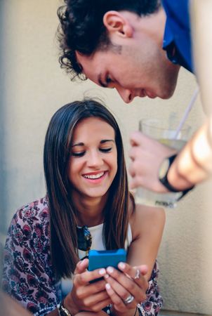 Smiling woman looking a smartphone with her friend outdoors
