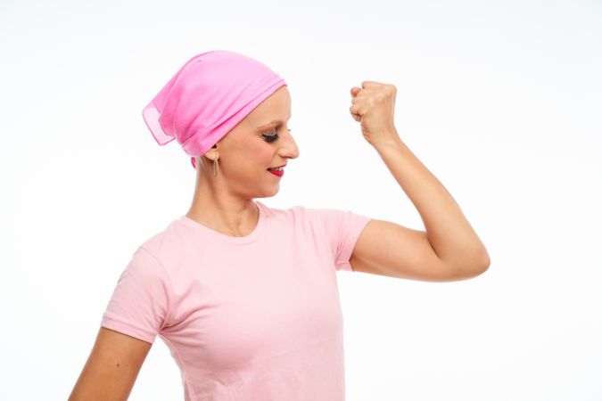 portrait of a woman with cancer with a pink scarf on her head, gesticulating with strength