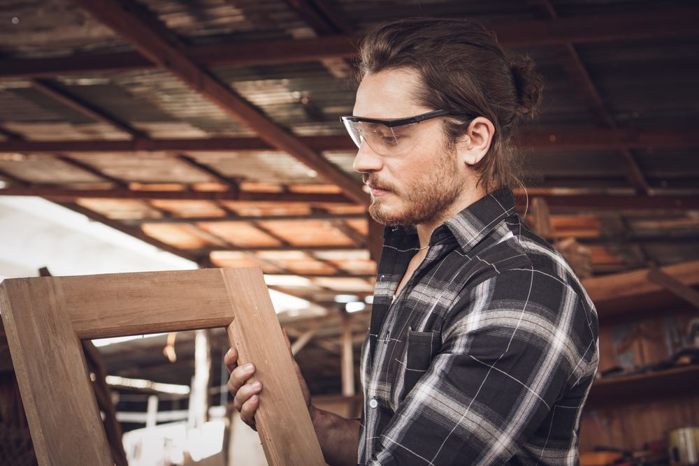 Male woodworker holding wooden frame he made in his workshop