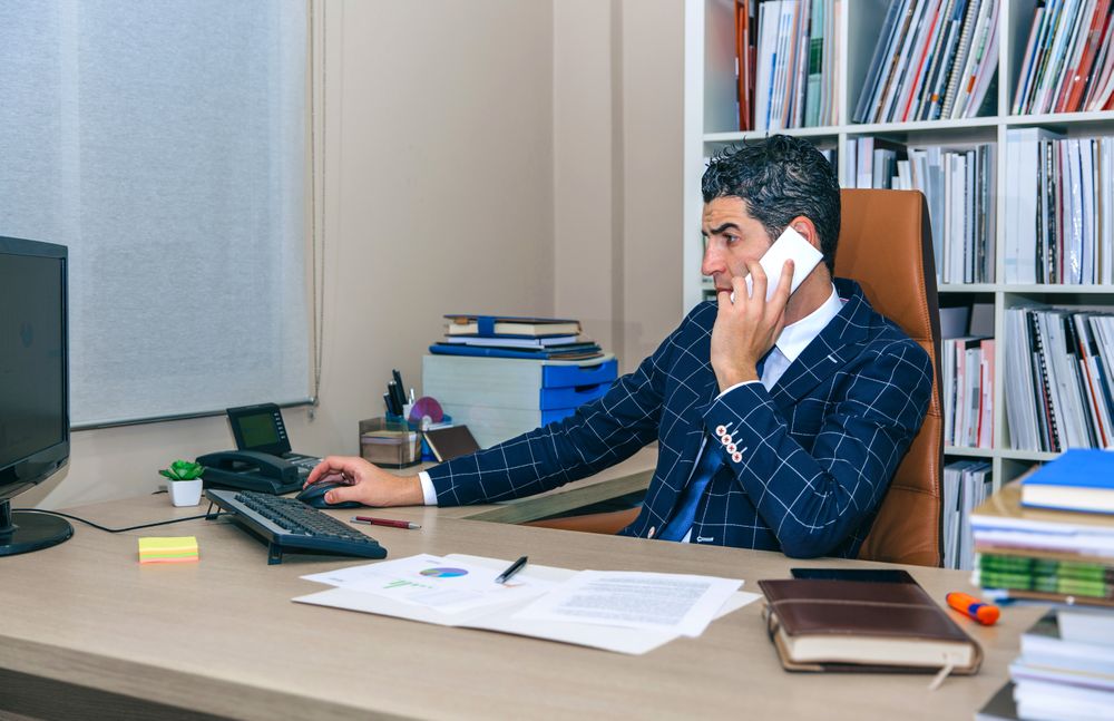 Businessman talking on smartphone and working on computer