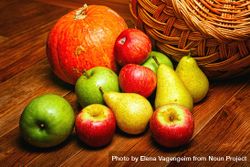 Autumnal fruit and squash on wooden table with wicker basket 5o8394