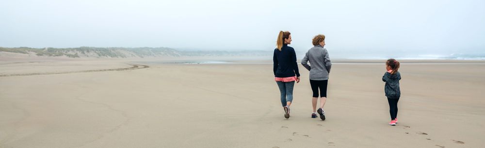Three generations of women walking on the beach
