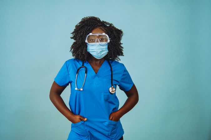Black female doctor standing with face mask, protective eyewear and stethoscope