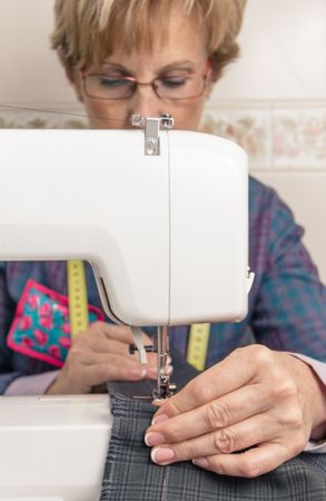 Mature seamstress woman working on sewing machine