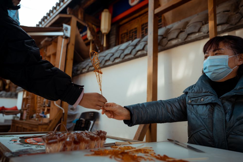 Woman with facemask handing an item to a person outdoor