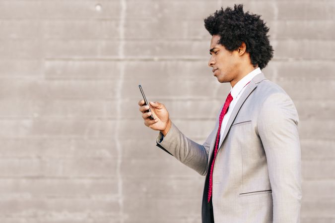 Side view of man in gray suit holding smartphone