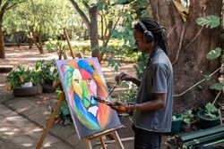 Black painter listening to music painting a picture outdoors