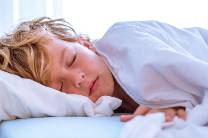 Ill boy sleeping on soft bed