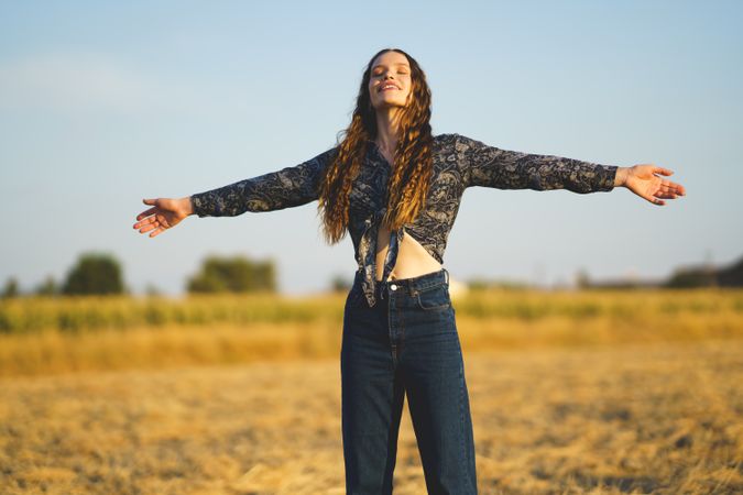 A Joyful Young Woman Happily Embracing the Beauty of Nature in a Beautiful Golden Field