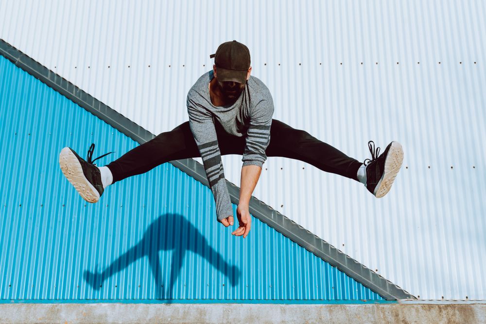 Trendy male flipping and jumping on street