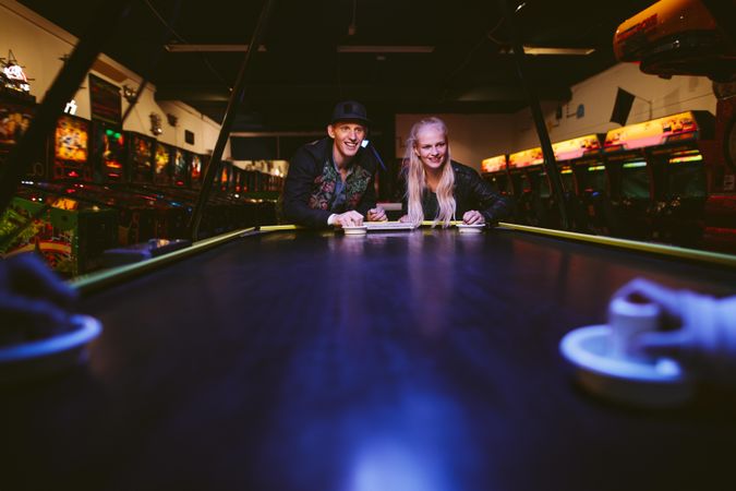 Man and woman playing a game of air hockey in the game room