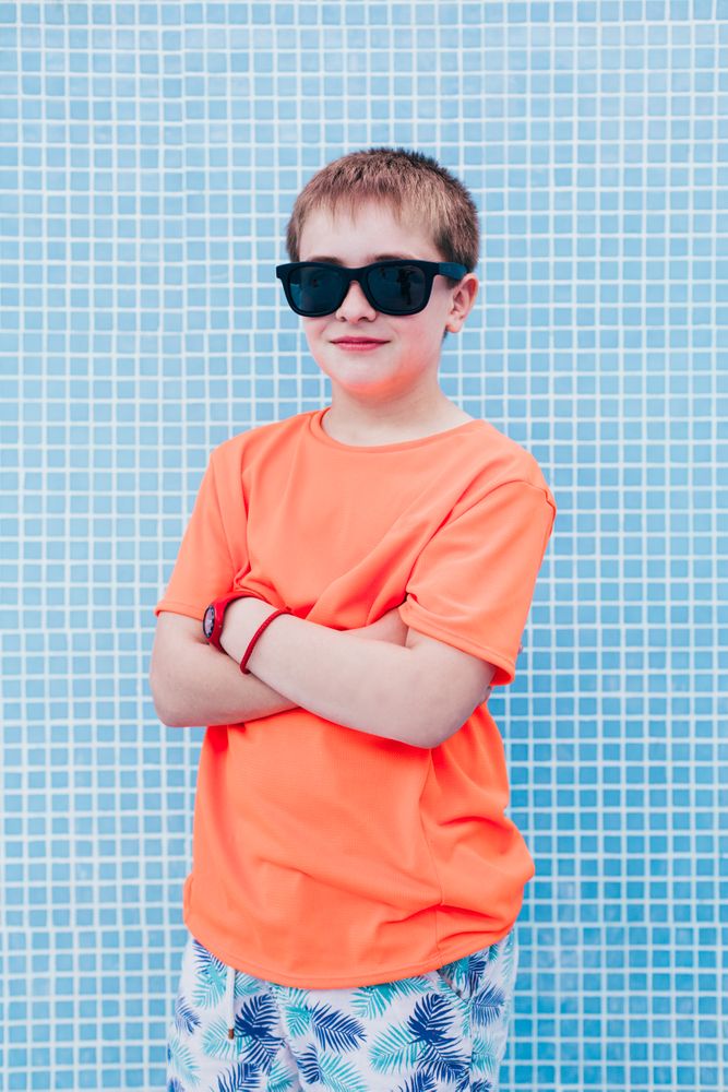 Happy boy in sunglasses against tiled wall