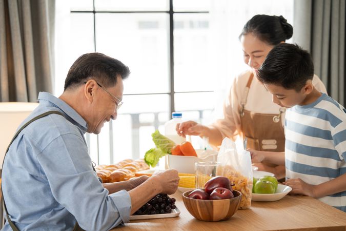 Asian grandparents support and help grandson cooking breakfast in the kitchen