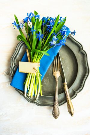 Spring table setting with blue scilla siberica over blue napkin