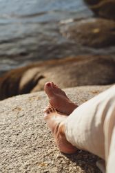 Person relaxing while sitting on stone