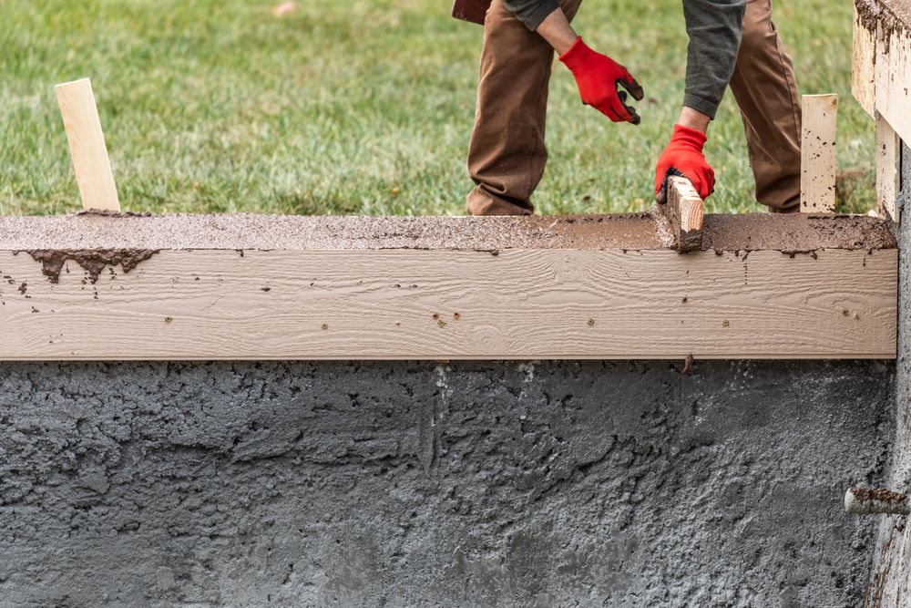 Construction Worker Leveling Wet Cement Into Wood Framing