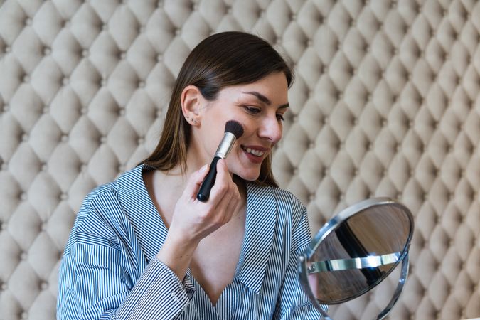Happy woman applying powder and recording video on camera