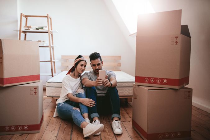 Young couple moving in new home and taking selfie