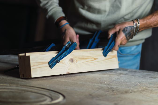 Anonymous craftsman fixing wooden boards with f clamps