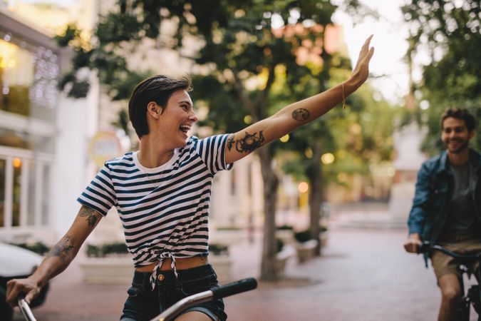Woman riding bicycle and waving back to a male friend