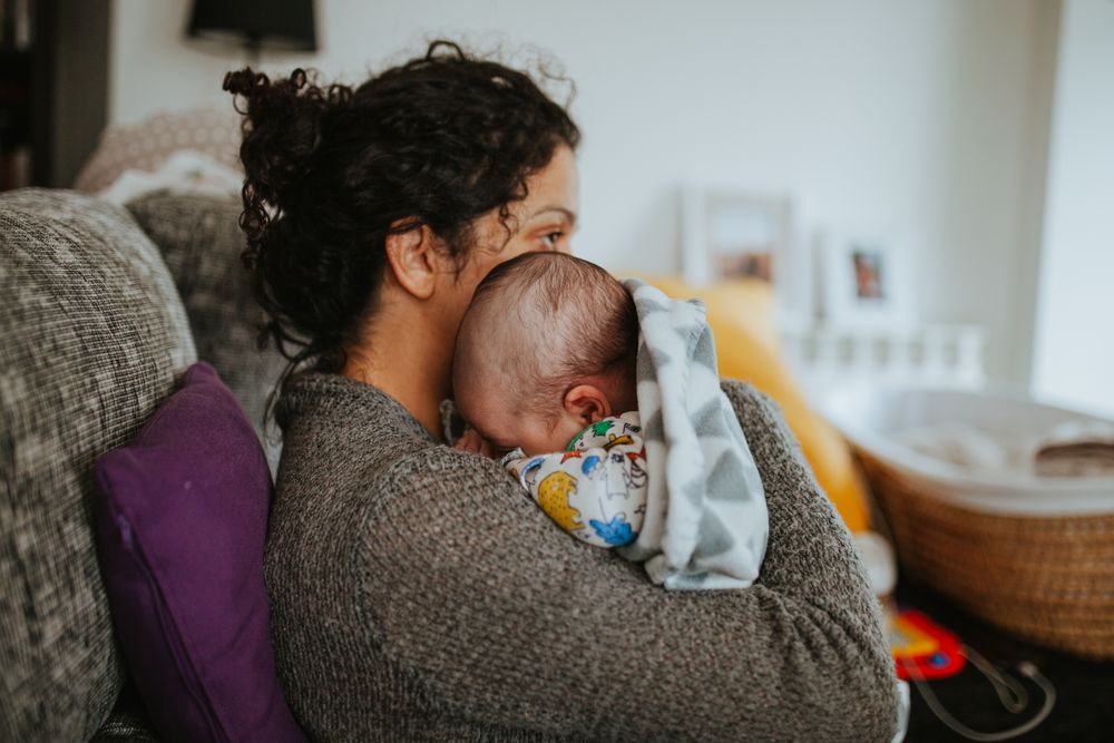 Side view of mother holding her newborn while sitting on the couch