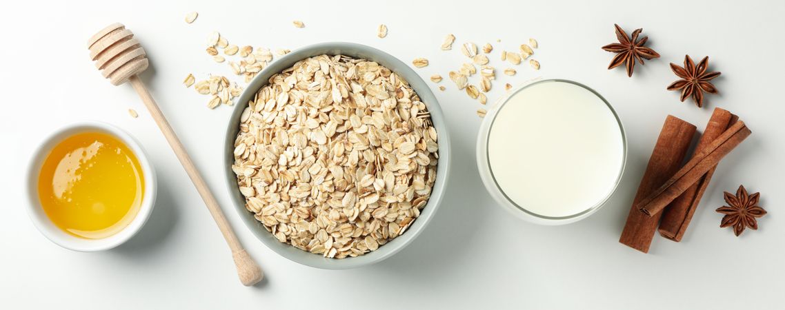 Composition with oatmeal flakes on plain background, top view. Cooking breakfast