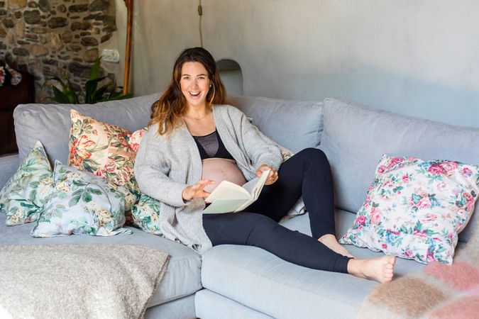 Pregnant woman relaxing on sofa with book
