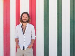 Cheerful guy standing near striped wall