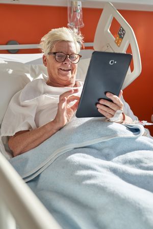 Happy woman using tablet during rehabilitation in hospita