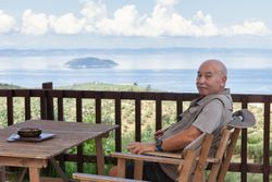 Relaxing man sitting on wooden terrace with seascape