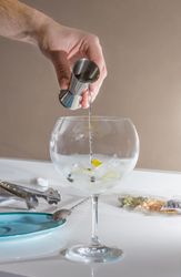 Barman pouring drink to prepare gin tonic cocktail
