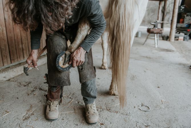 Crop farrier cleaning horse hoof