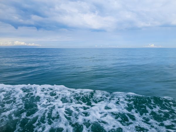 Calm sea view with cloudy sky and boat wake in Pariaman, Indonesia
