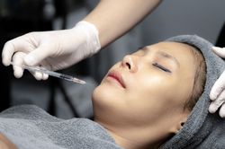 A young woman injects vitamins into her face in a beauty clinic.