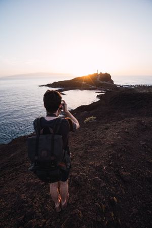Photographer picturing sunset above remote coast