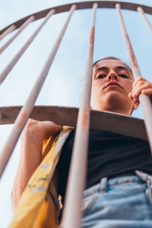 Thoughtful female leaning on metal fence