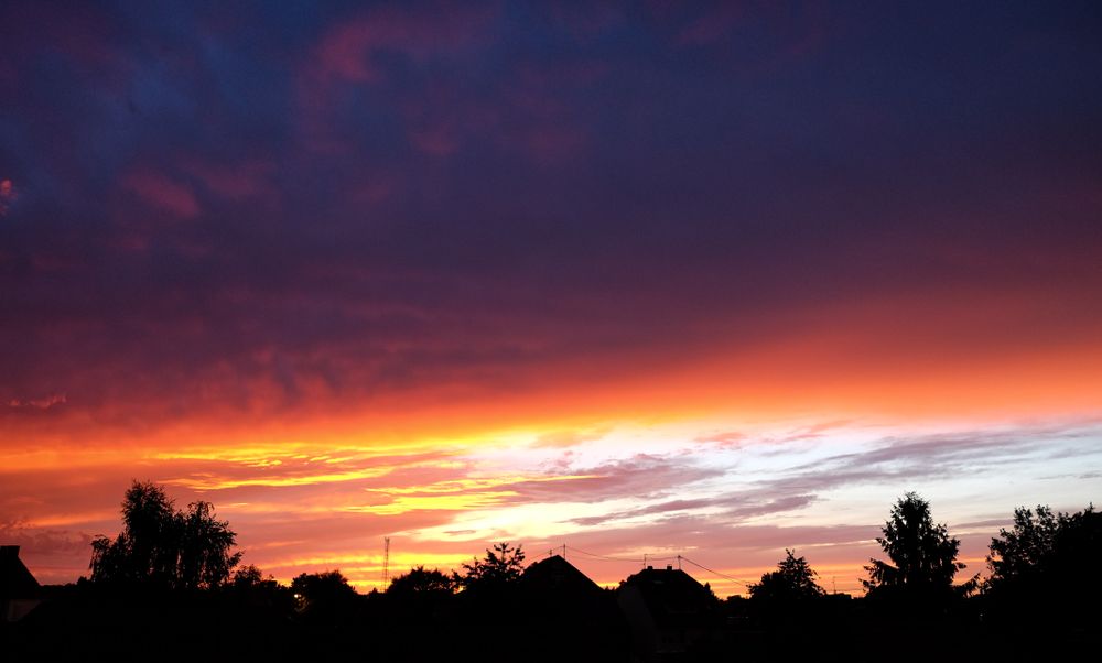 Vibrant purpler and yellow gradient sunset over rooftop silhouettes