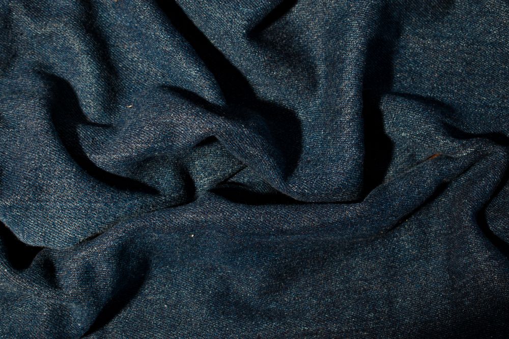 Close up detail crumpled wavy Navy blue jeans fabric background texture.