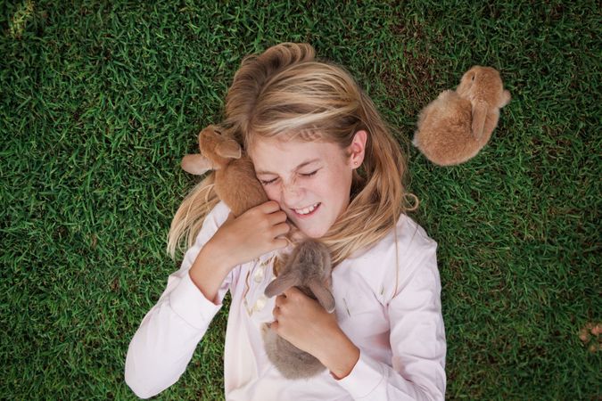 Girl cuddling with brown bunnies on grass