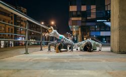 Women's sporting team doing push ups during training in the city at night