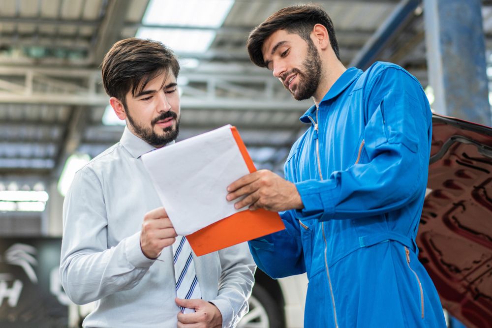 Mechanic explaining repairs to customer on clipboard