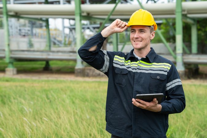 Refinery oil engineer worker in protection hardhat with digital tablet inspecting at petrochemical factory.